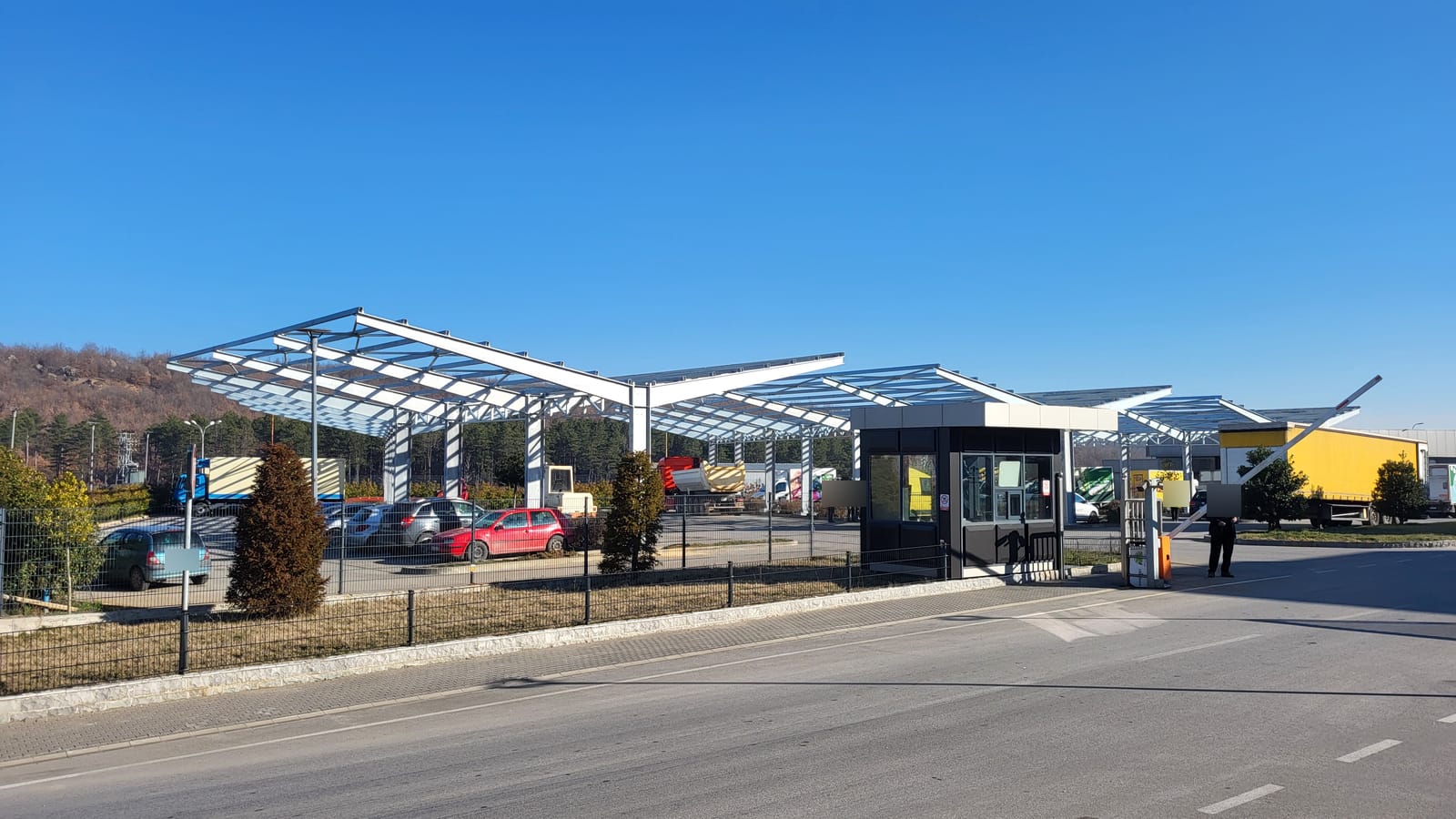 Stahlkonstruktion des Truckports hinter Zaun und Pförtnerhaus an der Einfahrt zum Gelände